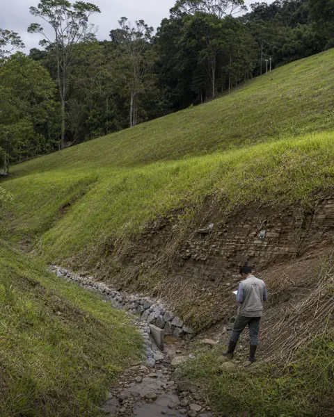 Profissional realiza uma avaliação de terreno junto a uma área de drenagem